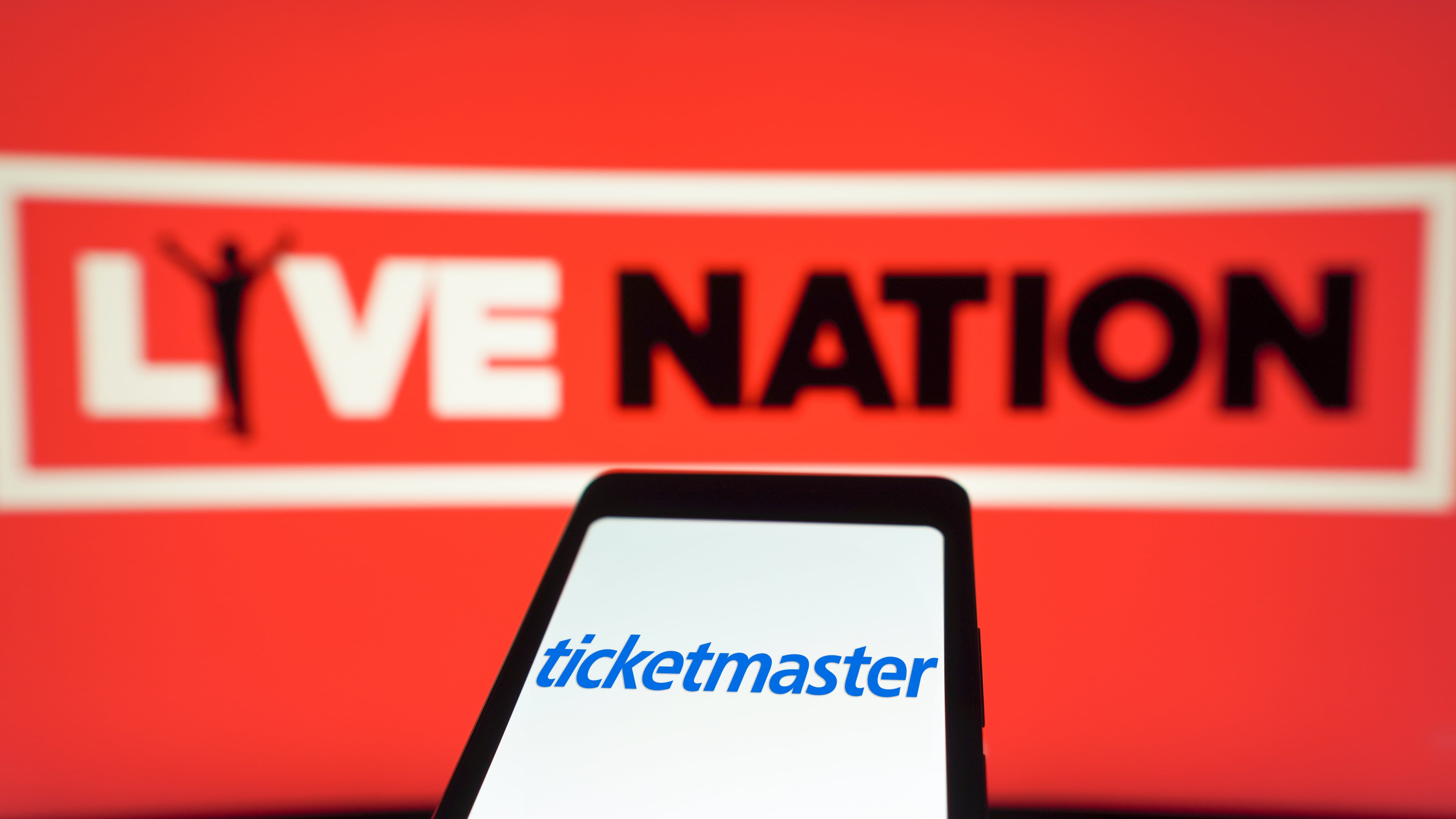 In this photo illustration, the Ticketmaster logo is displayed on a smartphone screen and Live Nation Entertainment in the background