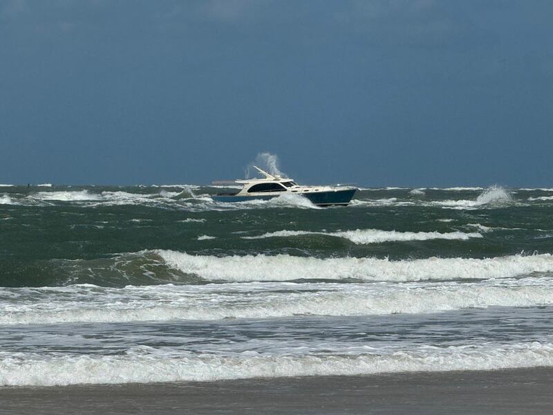 A boat with two people onboard takes on water at the Vilano Inlet.
