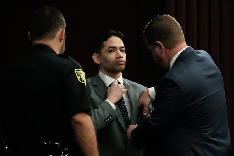 Defendant Mario Fernandez Saldana, center, fixes his tie and collar while talking with one of his defense attorneys Jesse Dreicer, right, before the start of jury selection in Saldana’s murder trial Monday morning, August 10, 2026 in the Duval County Courthouse in Jacksonville, Fla. [Doug Engle/Florida Times-Union]