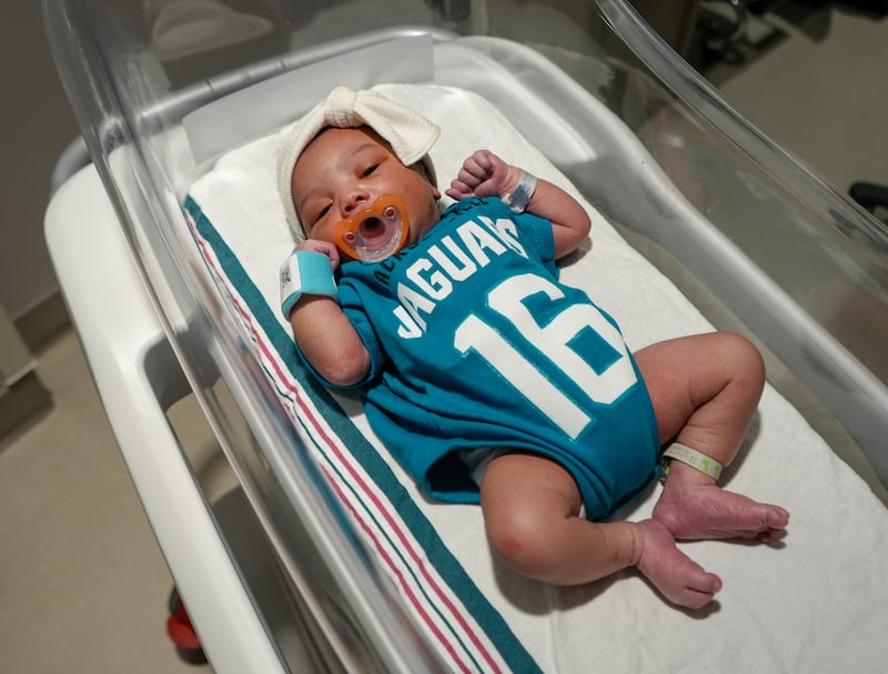 Babies from various local Baptist Health hospitals wearing Trevor Lawrence jersey onesies