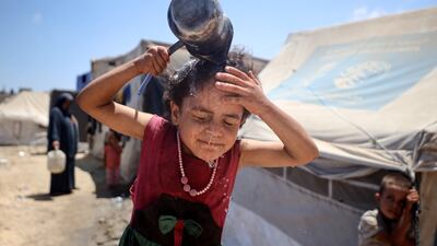 A displaced Palestinian girl is splashing her face with water in front of her tent during a heatwave in Deir al-Balah, in the central Gaza Strip, on July 8, 2024, amid the ongoing conflict between Israel and the Palestinian Hamas militant group. (Photo by Majdi Fathi/NurPhoto via Getty Images)