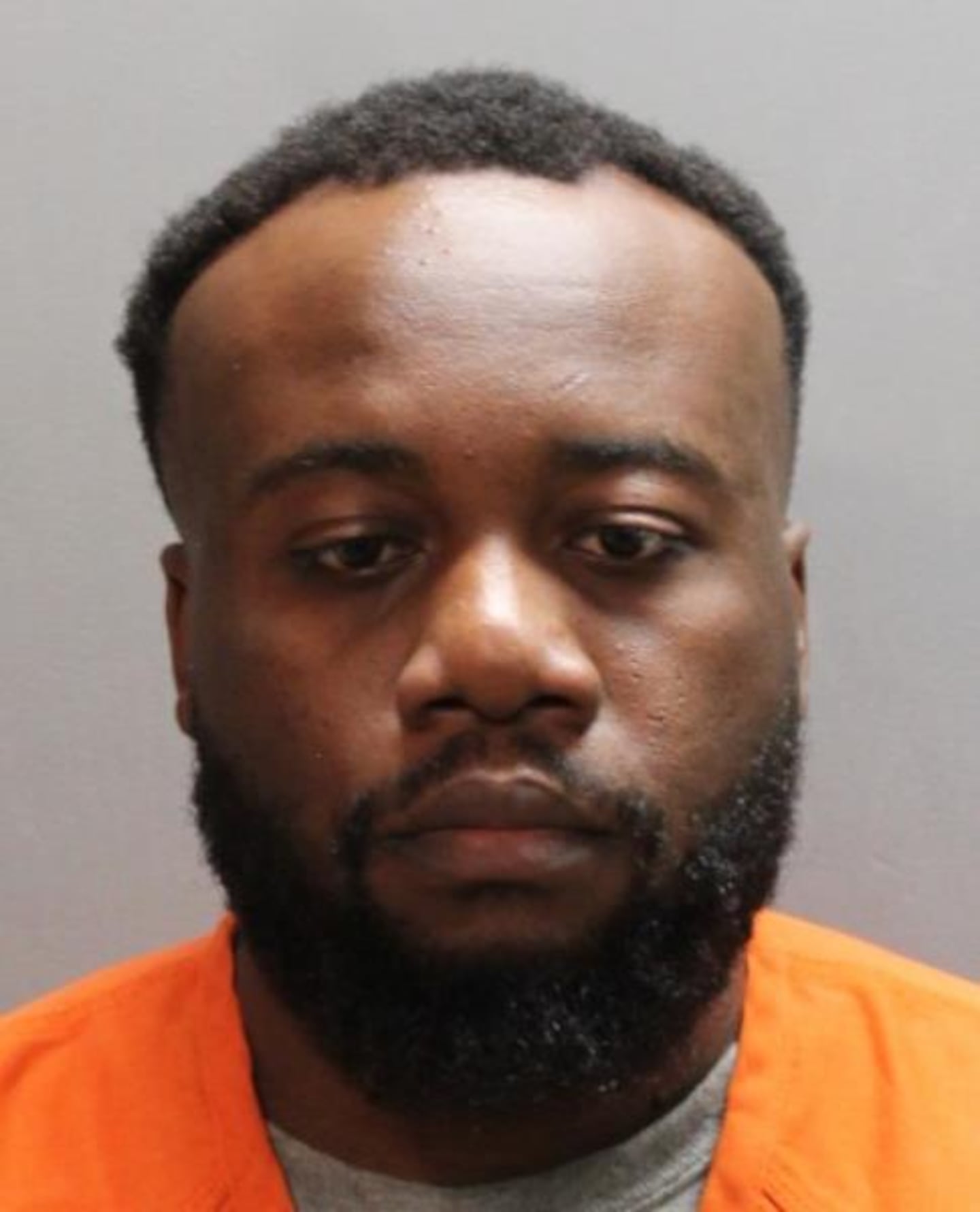 Christopher Bowens, an adult man with a thick black beard and short black hair in an orange inmate jumpsuit